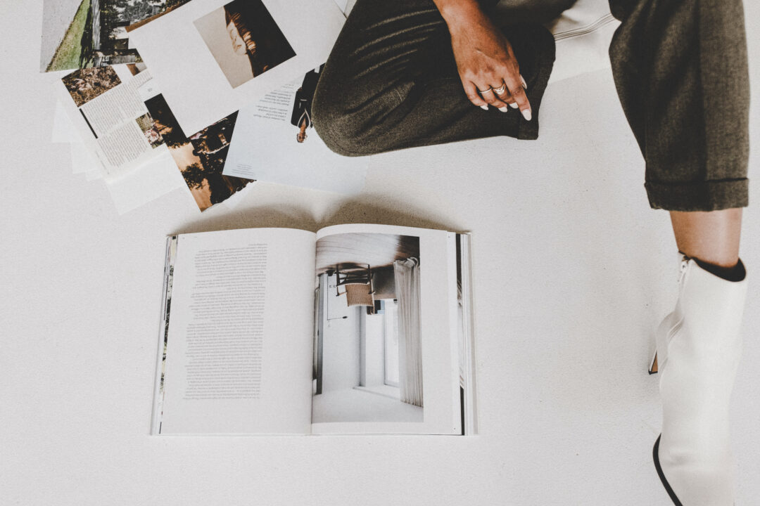 Draufsicht auf ein aufgeschlagenes Buch und ausgelegte Fotos auf dem Boden