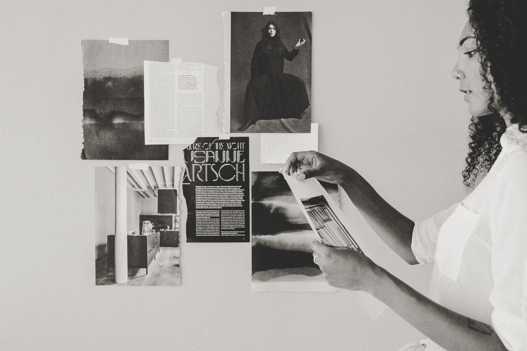 Frau heftet Seiten an eine Moodboard-Wand