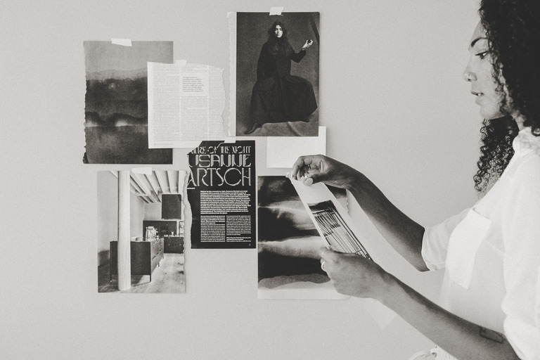 Frau heftet Seiten an eine Moodboard-Wand