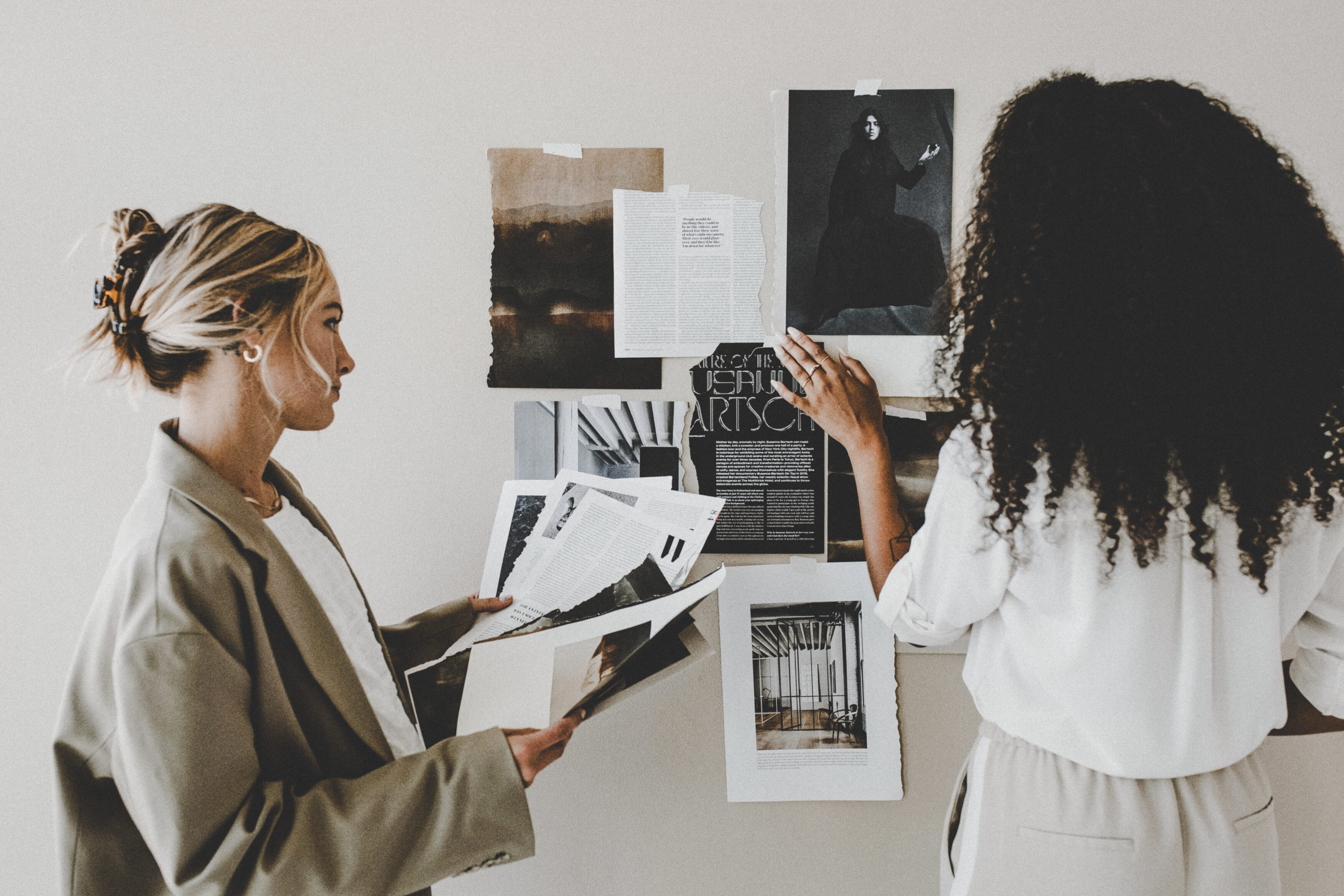 Zwei Frauen arbeiten gemeinsam an einer Moodboard-Wand