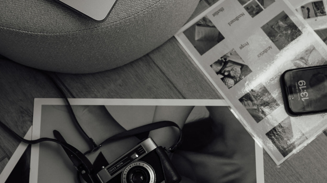 Analoge Kamera, Smartphone und Fotoabzüge auf einer grauen Decke