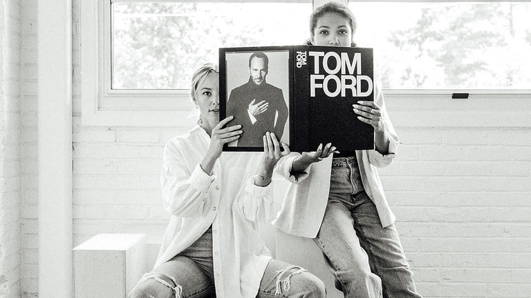 Zwei Frauen halten ein aufgeschlagenes Tom-Ford-Buch vor ihre Gesichter